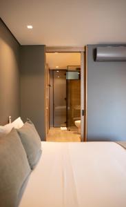 a bedroom with a white bed and a bathroom at Wake - branded residences in Medellín