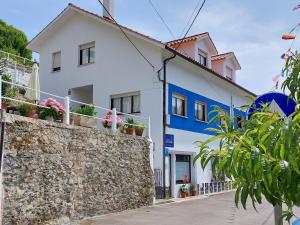 a white and blue building with potted plants on a wall at Pensión El Pozo in Cudillero