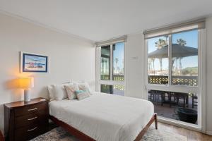 ein Schlafzimmer mit einem Bett und einem Balkon mit einem Sonnenschirm in der Unterkunft Belmont Ocean Views - Massive Private Deck, Grill & Parking in San Diego