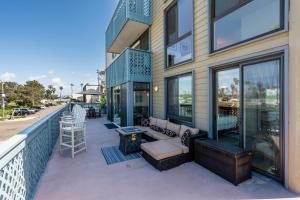 einen Balkon eines Gebäudes mit einem Sofa und einem Tisch in der Unterkunft Belmont Ocean Views - Massive Private Deck, Grill & Parking in San Diego