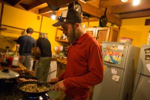 un hombre en una cocina preparando comida en una sartén en Hostal Las Natalias, en Futaleufú