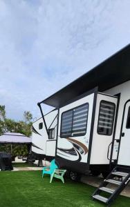 una caravana blanca estacionada en la hierba con una silla azul en So "Time to Wander" A pet friendly beach retreat, en Fort Myers