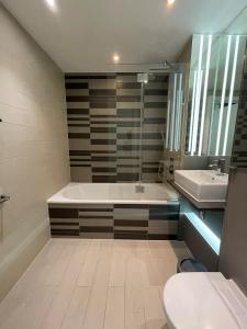 a bathroom with a tub and a toilet and a sink at Exquisite 2BD Flat w Balcony Shoreditch! in London