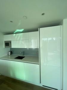 a kitchen with white cabinets and a sink at Exquisite 2BD Flat w Balcony Shoreditch! in London