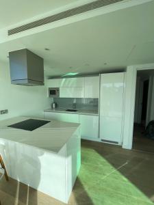 a white kitchen with white cabinets and a sink at Exquisite 2BD Flat w Balcony Shoreditch! in London