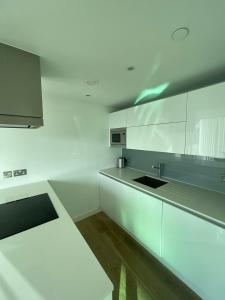 a white kitchen with white cabinets and a sink at Exquisite 2BD Flat w Balcony Shoreditch! in London