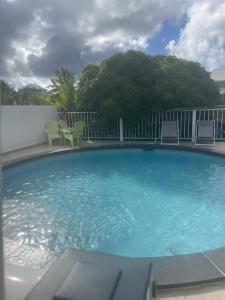 a large swimming pool with two chairs at Gîtes Soussoune in Anse-Bertrand