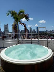 a hot tub on a rooftop with a palm tree at Manaíra Apart Hotel - 1606 in João Pessoa