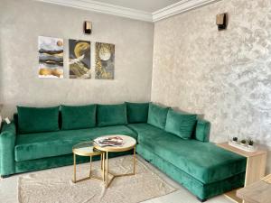 a living room with a green couch and a table at Bel appartement avec une belle vue sur la grande mosquée Hassan II et la mer in Casablanca