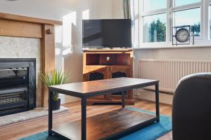 a living room with a table and a tv at Cottage Cross by YourStays in Macclesfield