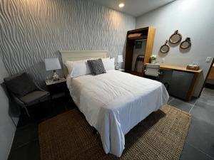 um quarto com uma grande cama branca e uma cadeira em Villas Quijote Valle de Guadalupe em Bonito