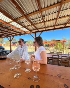 Villas Quijote Valle de Guadalupe في Bonito: رجل وامرأة يجلسان على طاولة مع كؤوس للنبيذ