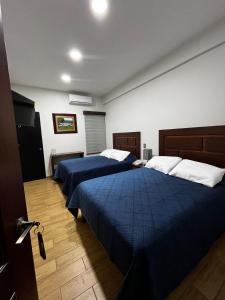 um quarto com 2 camas com lençóis azuis e almofadas brancas em Hotel&Salón RG em Tlapacoyan