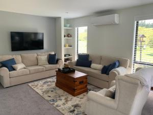 a living room with two couches and a tv at The Gate House in Tauranga