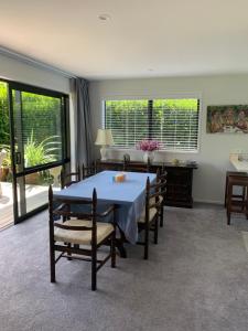 a dining room with a table and chairs and windows at The Gate House in Tauranga