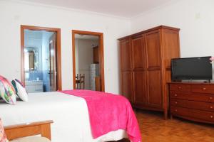 een slaapkamer met een bed en een dressoir met een tv bij Solar do Diabrete in Nazaré