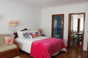 een slaapkamer met een bed met een rode deken en een stoel bij Solar do Diabrete in Nazaré
