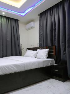a bedroom with a large bed with black curtains at JKA 1-BEDROOM-Apart 24HRS POWER Unlimited WIFI , GARDEN PATIO AREA ,FREE DAILY HOUSEKEEPING in Lagos