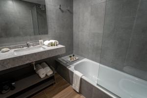 uma casa de banho com uma banheira, um lavatório e um espelho. em Barrancas Quality Apartments em Buenos Aires