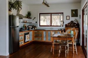 a kitchen with a table and a refrigerator at Kestrel Nest EcoHut in Mount Adrah