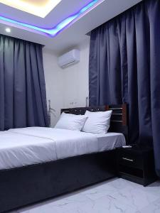 Schlafzimmer mit einem großen Bett und blauen Vorhängen in der Unterkunft JKA1-Bedroom Luxury Serviced Apartment in Lagos