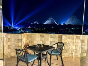 - une table et des chaises sur un balcon la nuit dans l'établissement Jumeirah pyramids view inn, au Caire