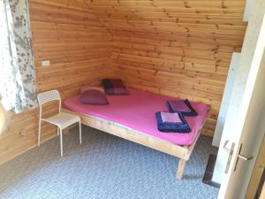 een kleine kamer met een roze bed en een stoel bij Toma pirts BRĪVDIENU in Ikšķile