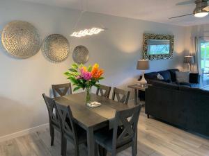 une salle à manger avec une table et un vase de fleurs. dans l'établissement Plantation Village # 64 Seven Mile Beach Fully Renovated Modern 2 Bed 2 Bath, à George Town