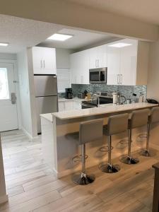 cocina con armarios blancos y barra con taburetes en Plantation Village # 64 Seven Mile Beach Fully Renovated Modern 2 Bed 2 Bath, en George Town