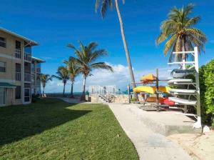 a view of a beach with palm trees and surfboards at Plantation Village # 64 Seven Mile Beach Fully Renovated Modern 2 Bed 2 Bath in George Town