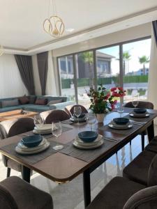 - une table en bois avec des assiettes et des verres à vin dans l'établissement Villa Blue - New Luxury Villa, à Belek
