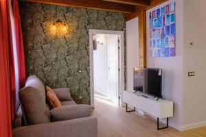 uma sala de estar com um sofá e uma televisão de ecrã plano em Apartamentos & Wellnes LA QUIMERA DE AITANA Burgo de Osma em El Burgo de Osma