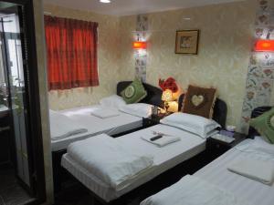 Habitación con 3 camas y mesa con lámpara. en Mabuhay Hotel en Hong Kong