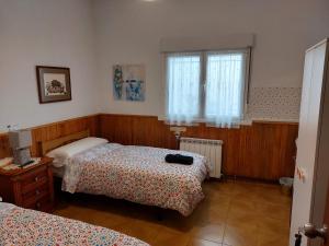 a bedroom with two beds and a window at Pensión El Pozo in Cudillero
