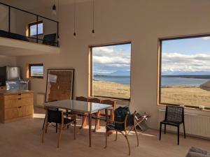 comedor con mesa, sillas y ventanas en Look Out - Loft, en Puerto Natales