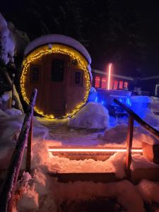 Wellnessoase Nordschwarzwald في Neuweiler: منزل مغطى بالثلج في الليل مع أضواء