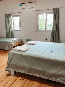 2 camas en una habitación con 2 ventanas en Los colibríes en Concepción del Uruguay