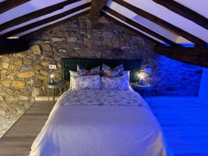 1 dormitorio con 1 cama grande en una pared de piedra en Casa Rural Vivienda Vacacional L´Andolina Complejo CaleaCabo, en Biescas
