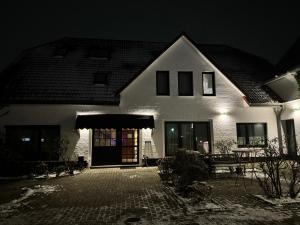 una gran casa blanca por la noche con un banco en Hotel Rademacher, en Wittmund