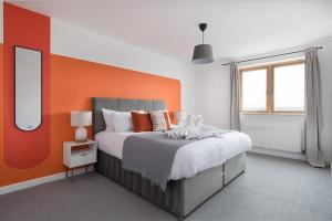 1 dormitorio con 1 cama con pared de color naranja en Luxury 2 bed, Central, Free Parking, Smart TV By Valore Property Services en Milton Keynes