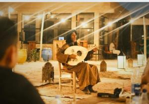 a man sitting in a chair with a guitar at The Original Camp in Aït Daoud