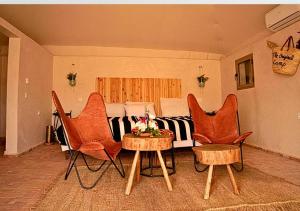 sala de estar con mesa, sillas y cama en The Original Camp en Aït Daoud