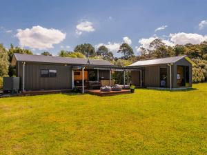 a home with a large yard with a house at Whangapoua Hideaway - Whangapoua Bach in Whangapoua