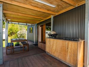 a covered deck with a grill and a table at Whangapoua Hideaway - Whangapoua Bach in Whangapoua