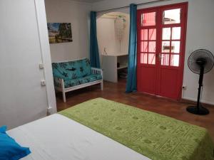 una camera con un letto, una porta rossa e una sedia di Bungalow Paradis Antillais (Do#) à moins de 10mn à pieds des plages a Le Gosier Altre 4 foto
