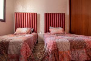 two beds in a room with red curtains and red sheets at Luxury Apartment with Pool in Agadir Bay 5 Min Walk to Beach in Agadir +28 photos