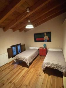 1 dormitorio con 2 camas y suelo de madera en Ático aires de gredos, en Candeleda
