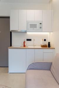 kuchnia z białymi szafkami i kuchenką mikrofalową w obiekcie CLIC suite and family w mieście Janina