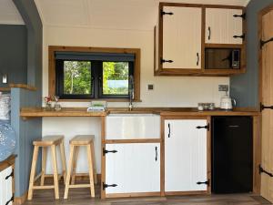 a kitchen with white cabinets and a counter with stools at Old Quay Escape in Tenby