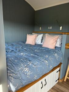 a bed with a blue comforter and pink pillows at Old Quay Escape in Tenby